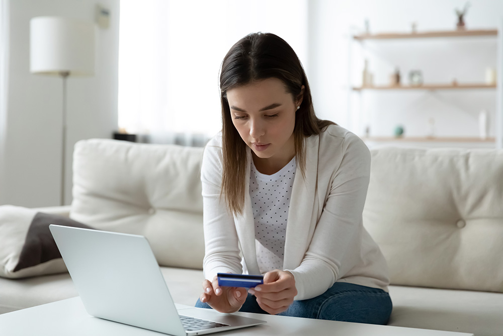 Woman holding a credit card while using a laptop